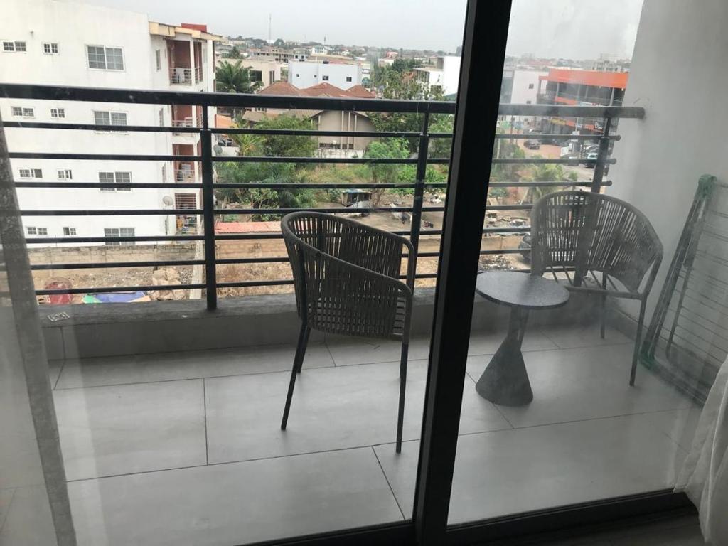 Un balcón con dos sillas y una mesa y una ventana. en Amal Suites, en Accra