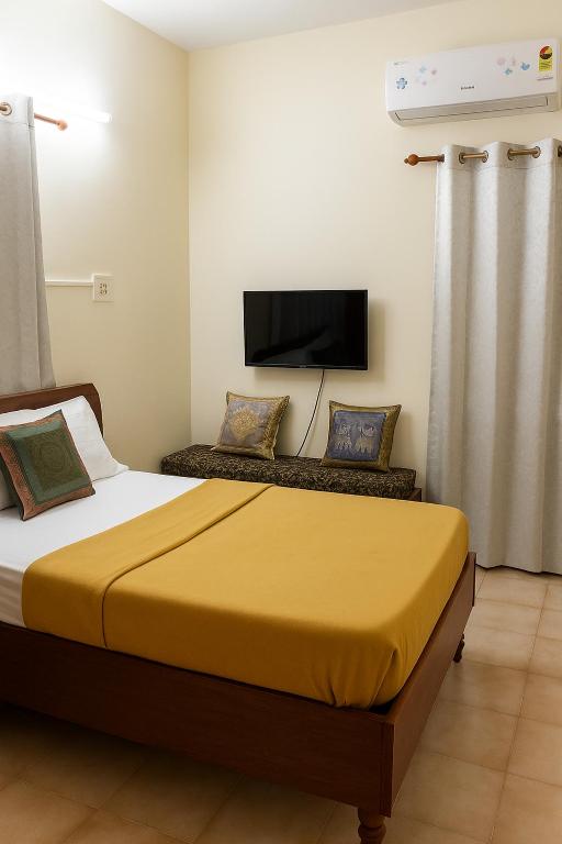 a bedroom with a bed and a flat screen tv at zest homes in Chennai