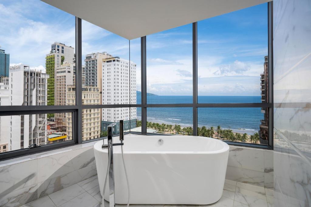 a bath tub in a bathroom with a view of the ocean at Avatar Danang Hotel in Danang