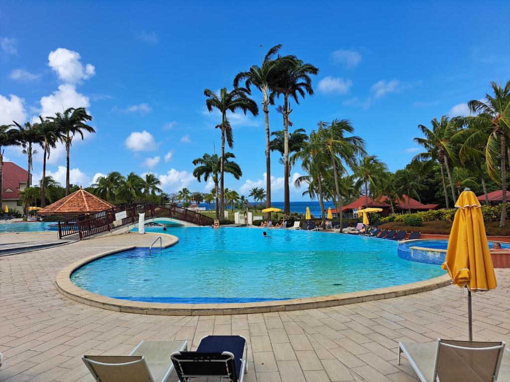 a pool at a resort with palm trees at DESIRADE 18 sainte luce in Sainte-Luce
