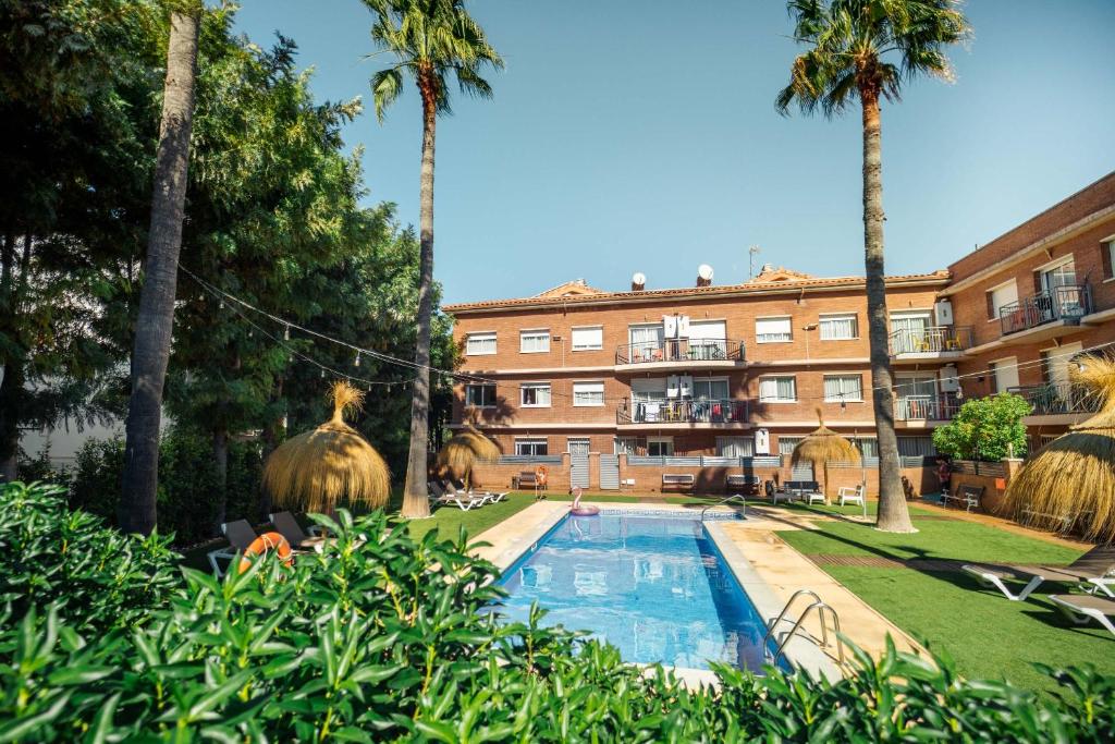 a hotel with a swimming pool in front of a building at Apartamentos Velor in Castelldefels