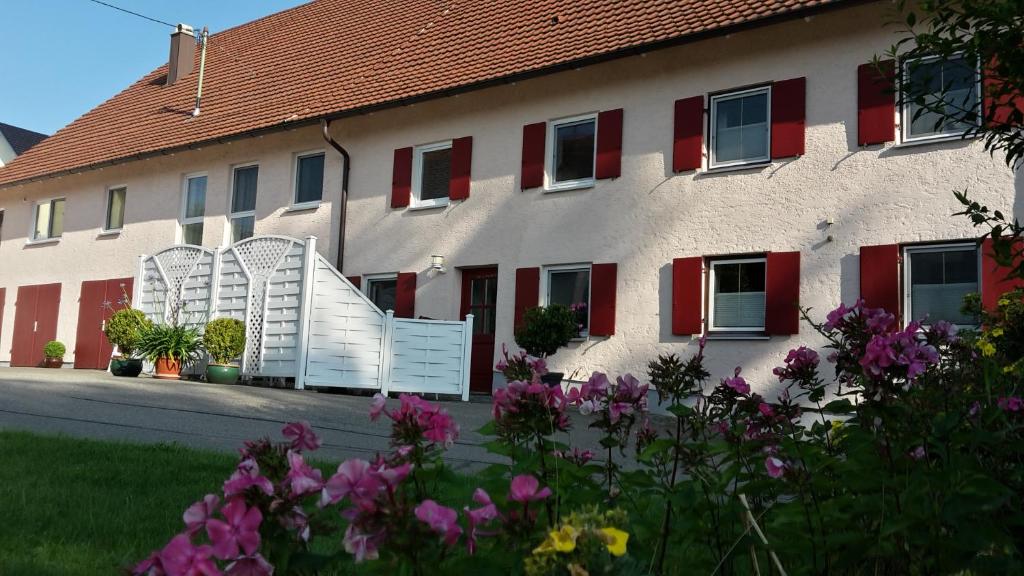 a building with red shutters and flowers in front of it at Allgäu Apartment in Memmingen