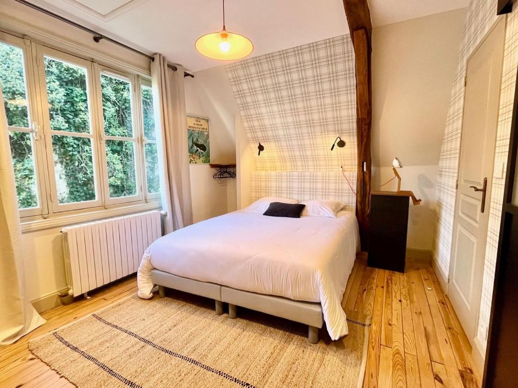 a bedroom with a white bed in a room with windows at Studio Dépendance du Château - Kitchenette in Gennes