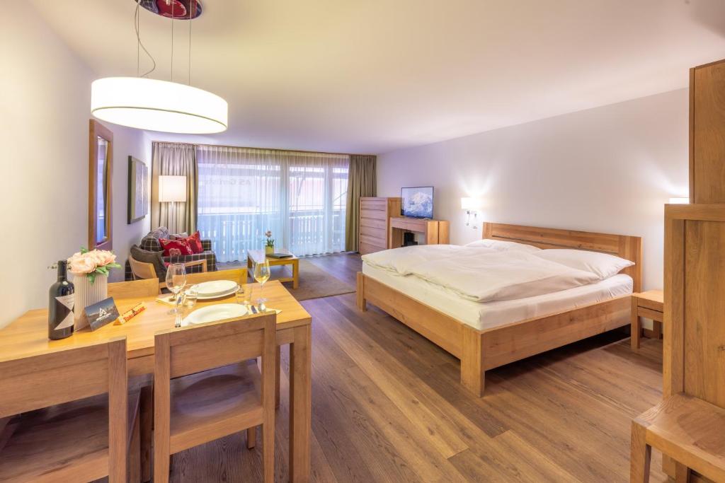 a bedroom with a bed and a table and a dining room at City Peak 2 Studio - in the heart of Zermatt in Zermatt