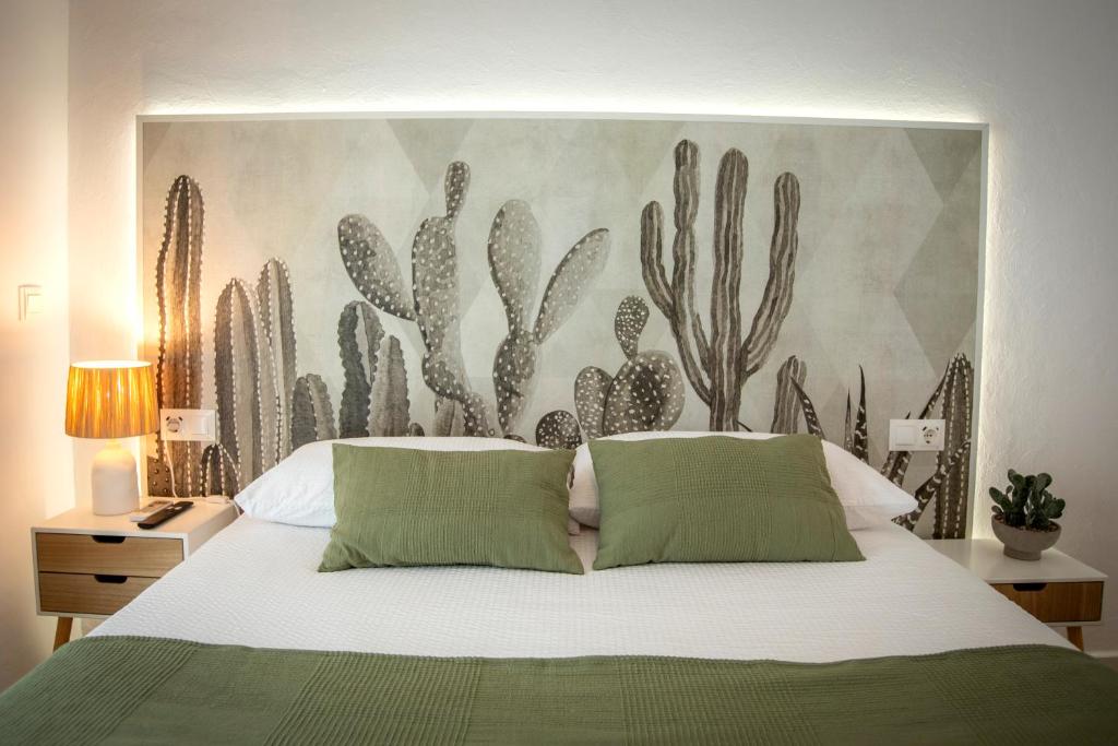 a bedroom with a bed with a cactus mural on the wall at Babel 11 Centro in Vélez de Benaudalla
