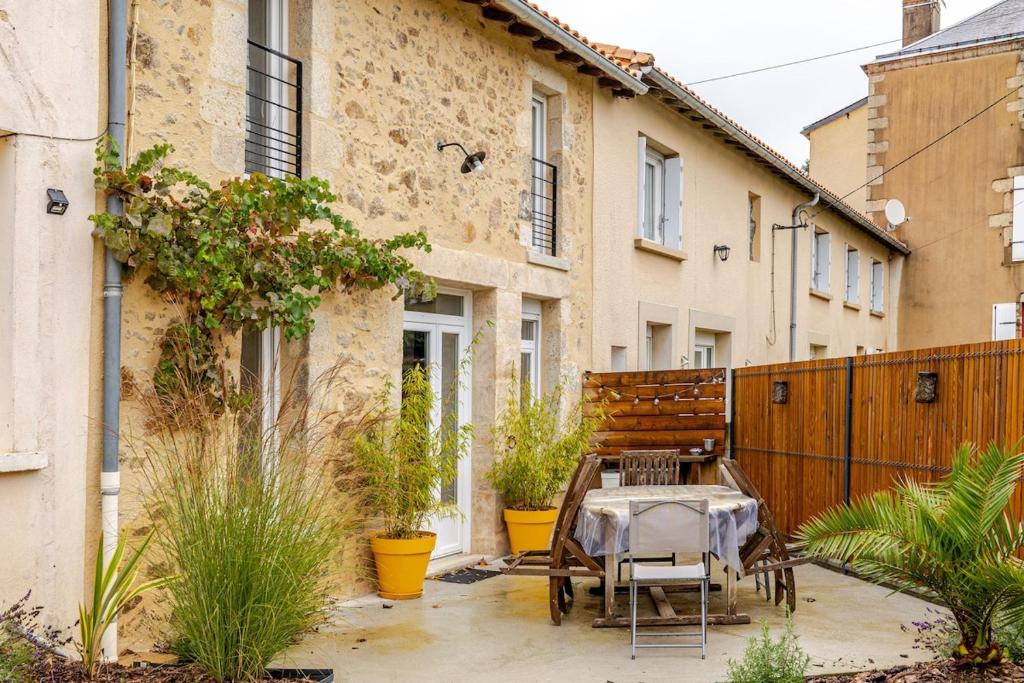a patio with a table and chairs in front of a building at L'Atelier Jolie maison de charme proche Puy duFou in La Flocellière