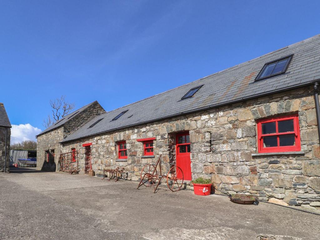 a stone building with red windows and a red door at Ty Gwartheg in Dinas