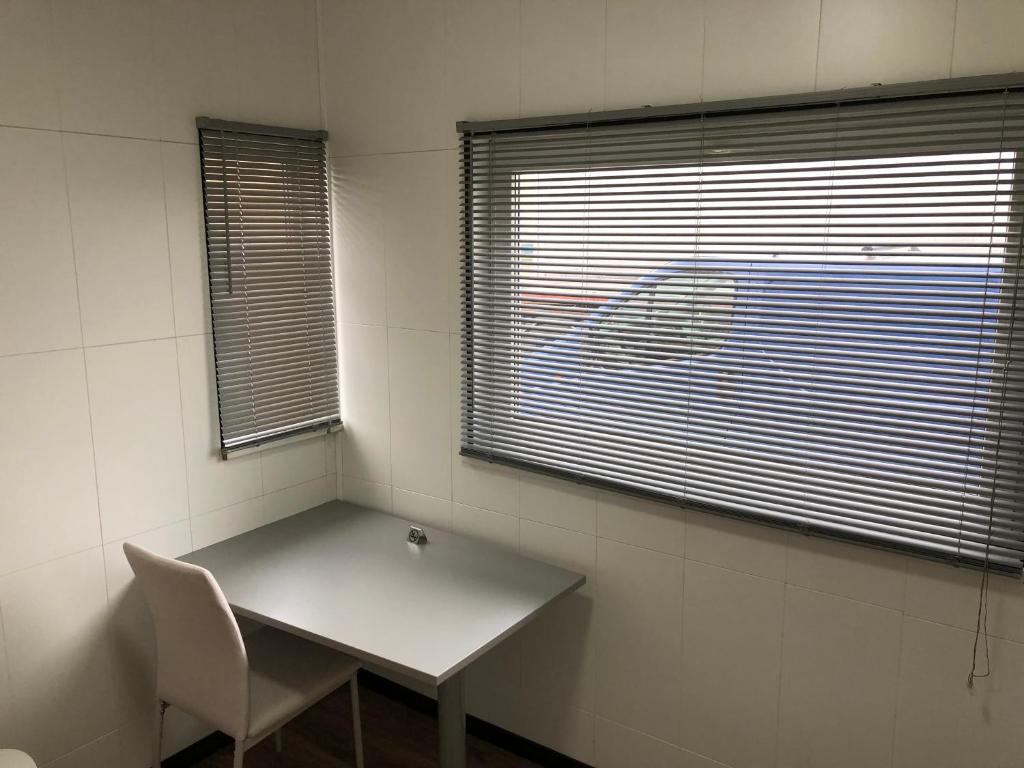 a table and a chair in a room with two windows at Drive inn Room&Shower in Rīga