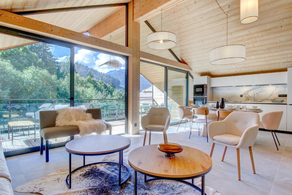 ein Wohnzimmer mit Tischen und Stühlen und einem großen Fenster in der Unterkunft Escapade luxueuse avec jacuzzi et sauna au cœur du domaine des Portes du Soleil in Montriond