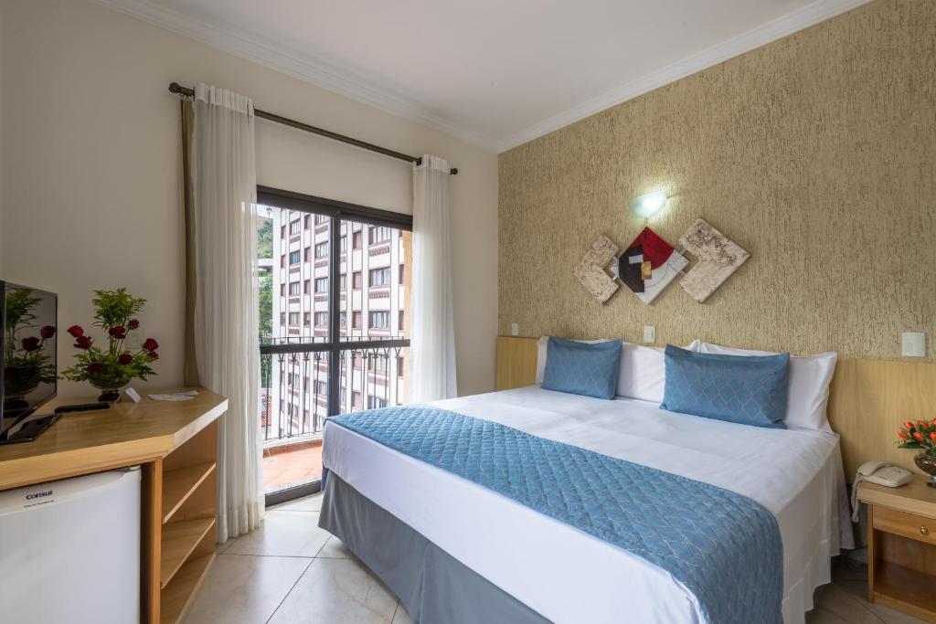 a bedroom with a bed and a large window at Hotel Guarany in Águas de Lindoia