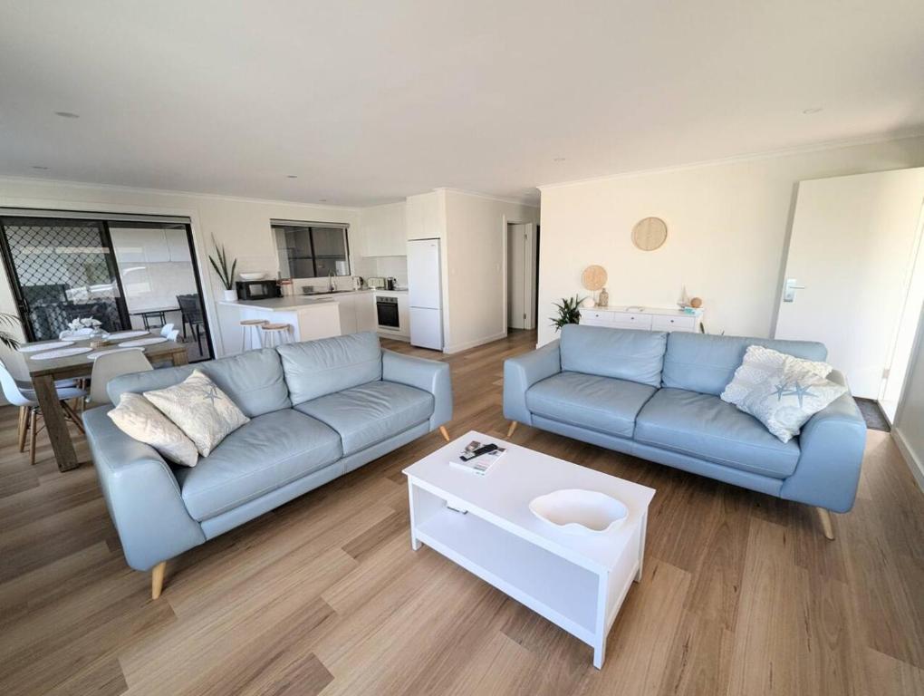 a living room with a blue couch and a table at Sails in the heart town walk to beach and coffee in Kingscote