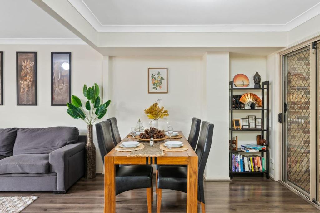 ein Wohnzimmer mit Tisch und Couch in der Unterkunft 3BR Townhouse Stylish Living in Sunnybank Hills in Brisbane