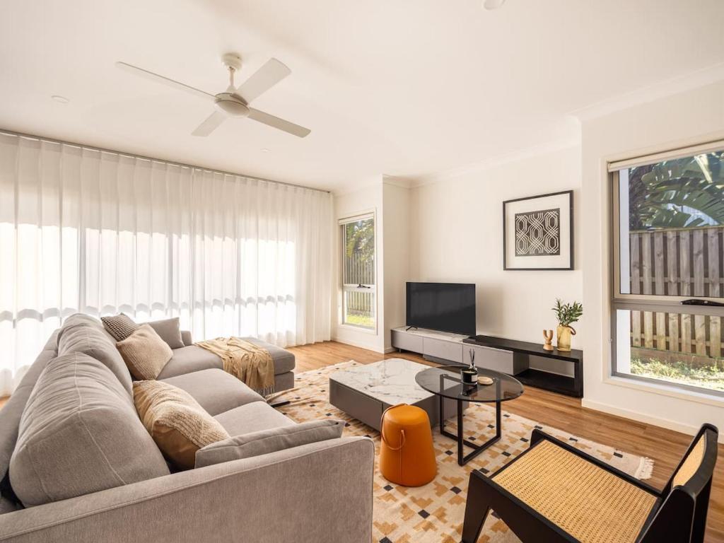 een woonkamer met een bank en een tv bij Elegant 5BR Family Home Modern Comfort in Rochedale in Rochedale