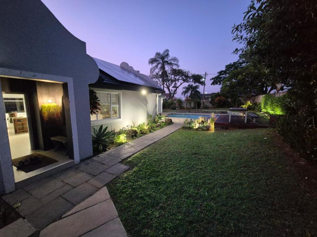 een achtertuin van een huis met een gazon en een zwembad bij Goodholme Guesthouse - Modern Spacious Peaceful in Durban