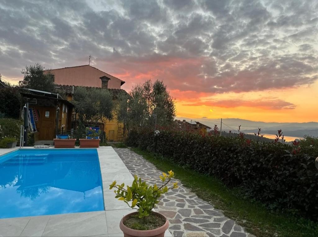 a house with a swimming pool and a sunset at Il Podere di Massi in Barberino di Mugello