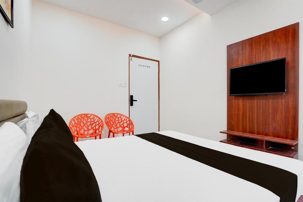 a bedroom with a bed and a flat screen tv at Hotel O Railway in Vadodara