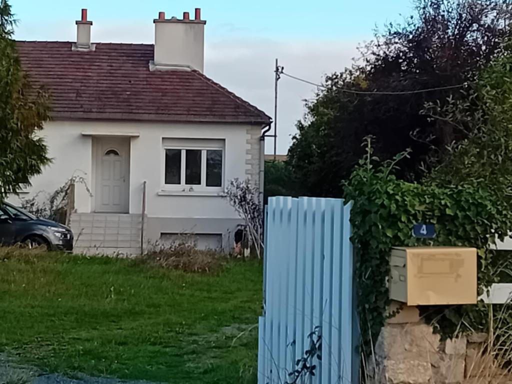 una casa blanca con una valla azul delante de ella en maison en banlieue de Caen, en Sept-vents