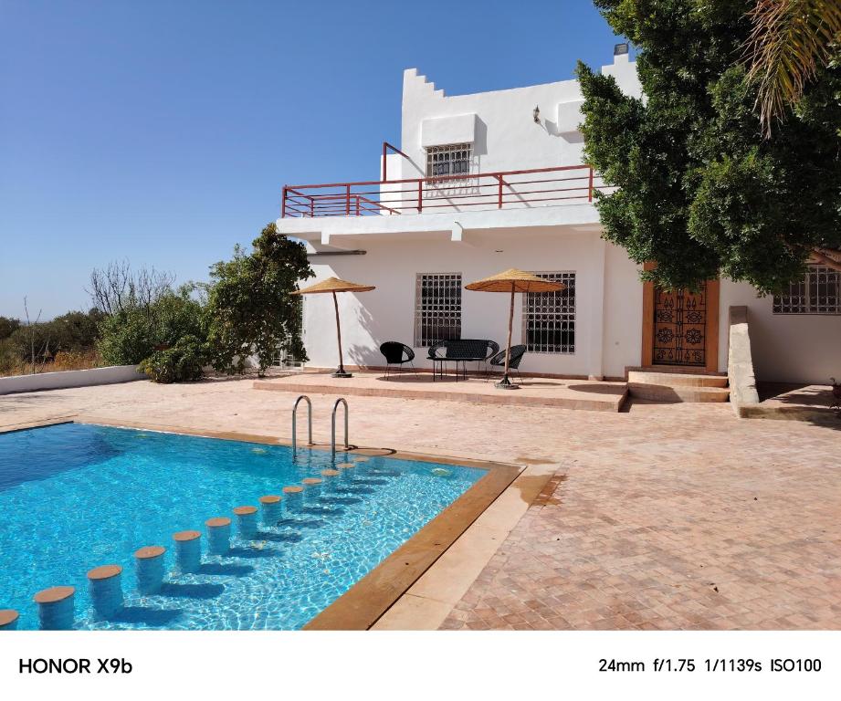 a villa with a swimming pool in front of a house at Ferme d'hôtes Aghbalou in Sefrou