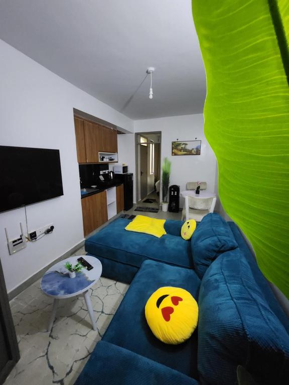 een woonkamer met een blauwe bank en gele kussens bij Poshairbnb in Nairobi