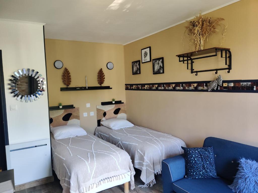 グレウー・レ・バンにあるStudio lumineux proche des thermes et du centre-village residence Parc Paradisのベッド2台と青いソファのある寝室
