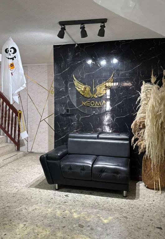 a black leather couch in front of a wall with a logo at Neoma Houses in Cali