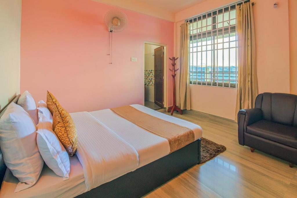 a bedroom with a bed with a chair and a window at Arara Group Alliance Stay in Cherrapunji