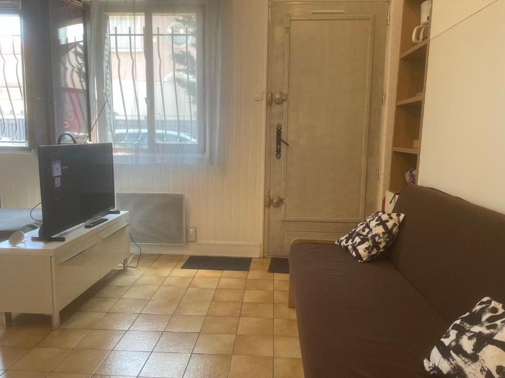 a living room with a couch and a television at Studio 20m2 Ground Floor street in Colombes