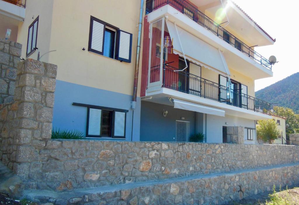a house with a stone wall next to a building at Διαμέρισμα στην φύση in Kiriákion