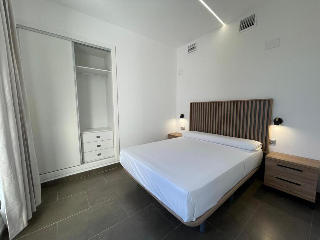 a white bedroom with a bed and a window at Palm Suites Gran Vía in Alicante