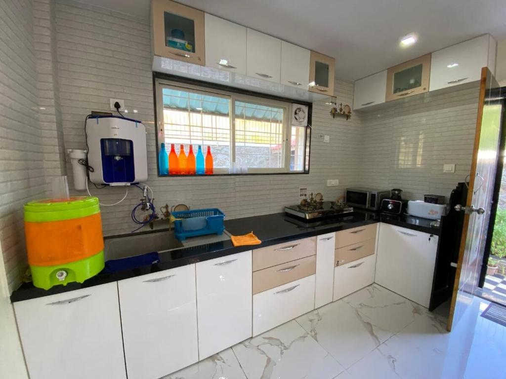 a large kitchen with white cabinets and a sink at BFMS Villa, Royal Purandar in Purandhar