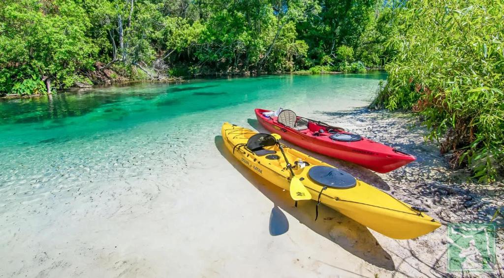 two kayaks sitting on the shore of a river at Oyster House Waterfront 3b2b Kayaks BBQ Games in Hernando Beach