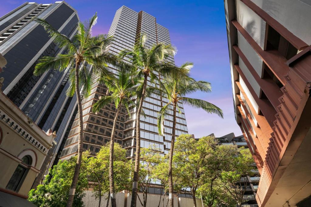 een groep palmbomen voor hoge gebouwen bij Chic DT Honolulu Executive Condo condo in Honolulu
