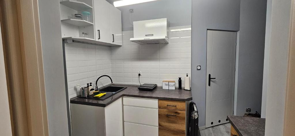 a small kitchen with white cabinets and a sink at Przytulny pokój jednoosobowy ze wspólną łazienką i kuchnią in Kętrzyn