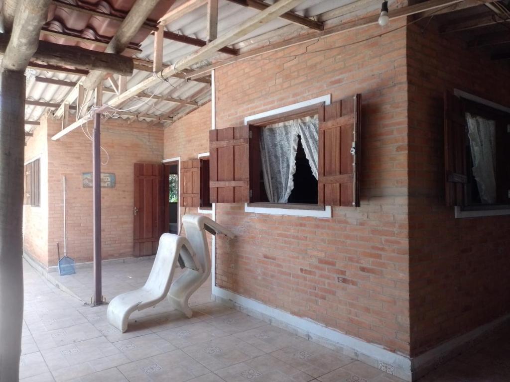 a brick wall with two white chairs in a room at Sitio Recanto das águas in São João del Rei