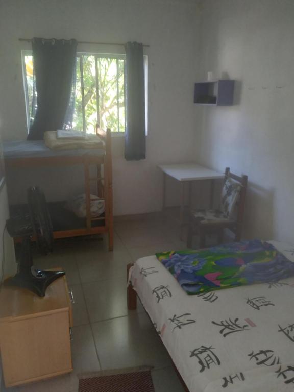 a bedroom with a bed and a table and a window at Xixova hostel in São Vicente