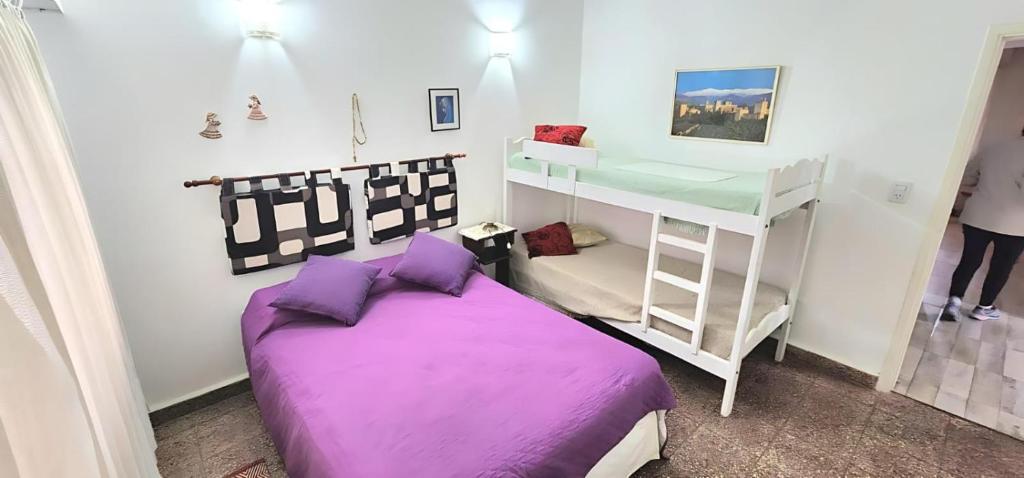 a bedroom with a purple bed and a bunk bed at Departamento de 2 Dormitorios con Cochera Cubierta WIFI Aire Acondicionado está bien Céntrico y a Metros del Mar in San Bernardo