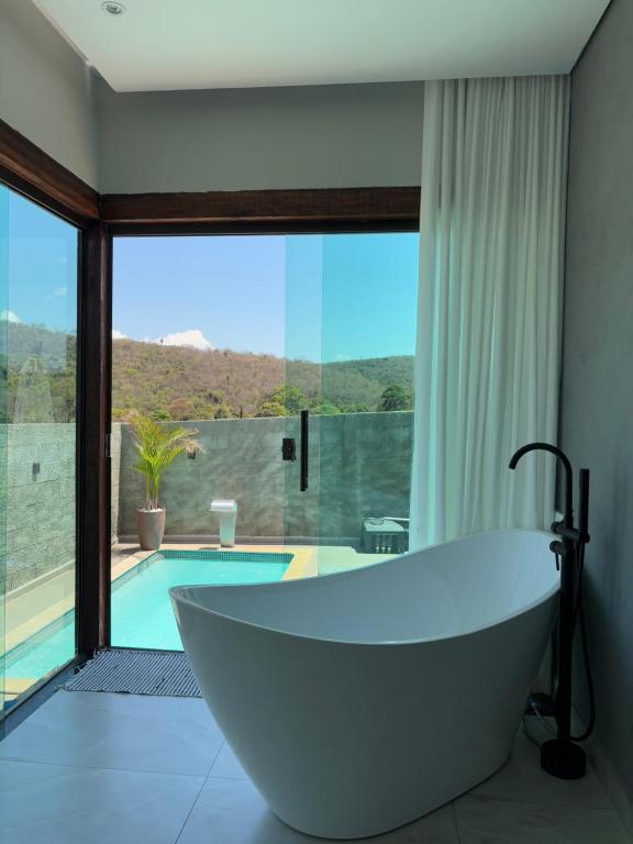 a bath tub in a bathroom with a pool at Cipó Lofts - Serra do Cipó in Santana do Riacho