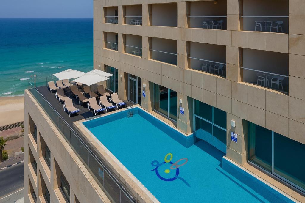an overhead view of a hotel with a swimming pool and the ocean at מלון ארנה בת ים - לאונרדו לשעבר in Bat Yam