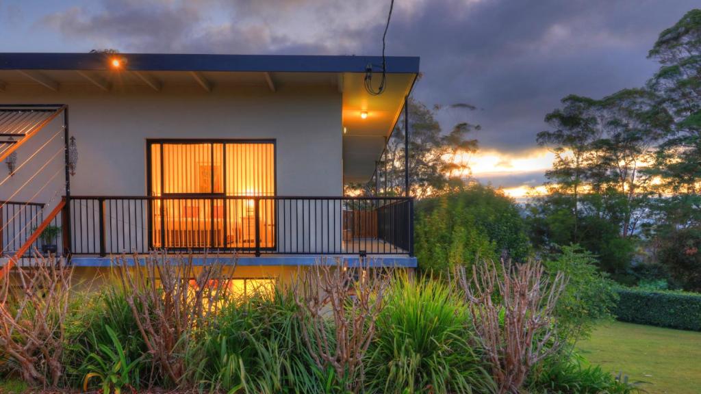 a house with a balcony in a garden at Mapleton Falls Accommodation in Mapleton