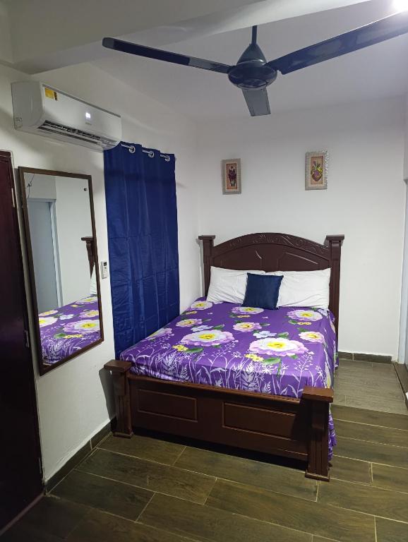 a bedroom with a bed with a purple comforter and a mirror at Apart hotel Costa Verde,#1 Exclusivo y seguro con cama Queen in Las Galeras