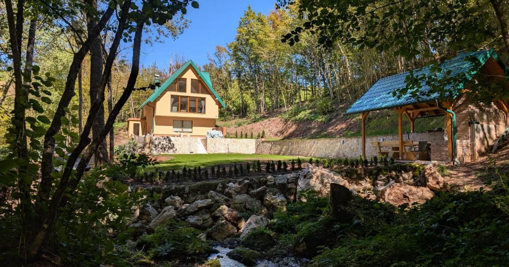 une maison dans les bois avec une rivière en face dans l'établissement Vila Presjenica, à Bunovci