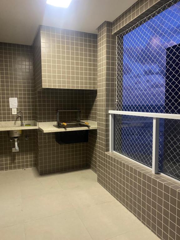 a tiled bathroom with a sink and a window at Apartamento frente á praia - vista incrível e conforto in Praia Grande