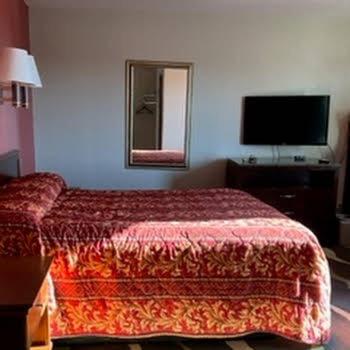 una habitación de hotel con una cama y un espejo en Budget Inn, en Wentzville