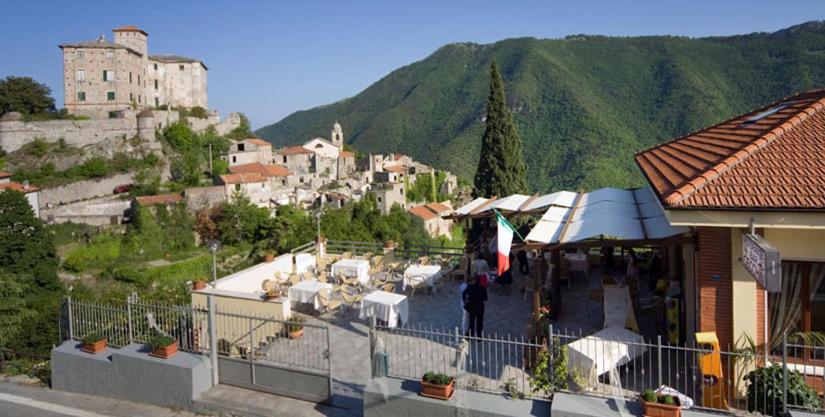 eine Person, die vor einem Gebäude mit einem Berg steht in der Unterkunft Albergo Cecchin in Balestrino