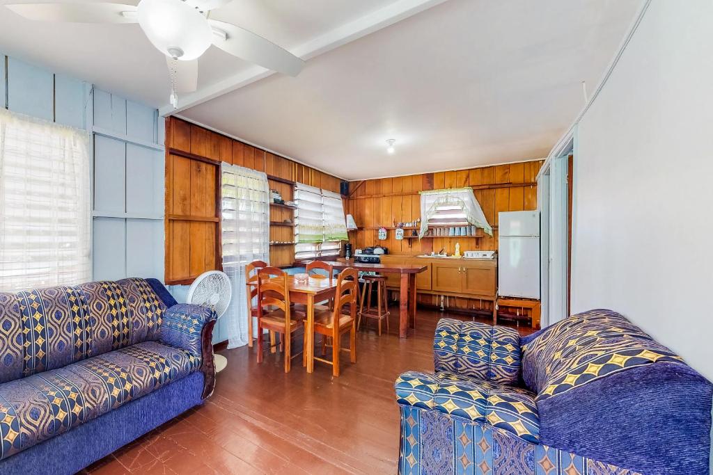 a living room with two couches and a kitchen at Tarpon at Carol's Cabanas -Gold Standard Certified in Placencia Village