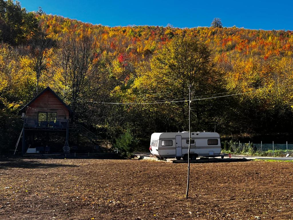 une remorque blanche garée devant une cabane dans l'établissement Camping Kosovo Treehouse campground of anykind, à Ferizaj