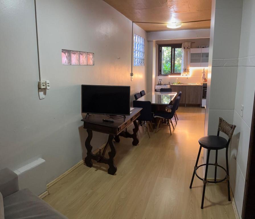 a living room with a television and a table with chairs at AP totalmente mobiliado, equipado e confortável in Bento Gonçalves