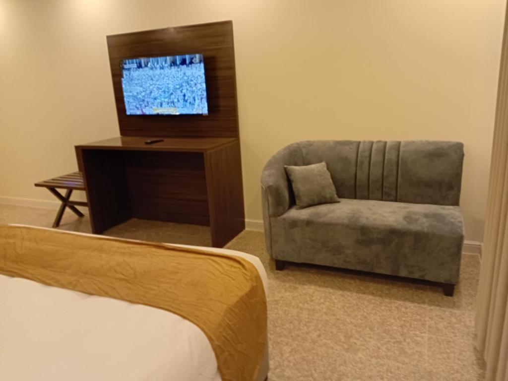 a bedroom with a bed and a chair and a television at مجمع مهنا in Tabuk