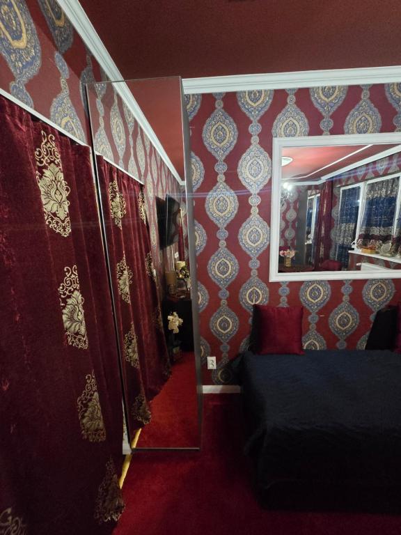 a room with red and gold wallpaper and a mirror at JEVA Apartman in Hajdúszoboszló