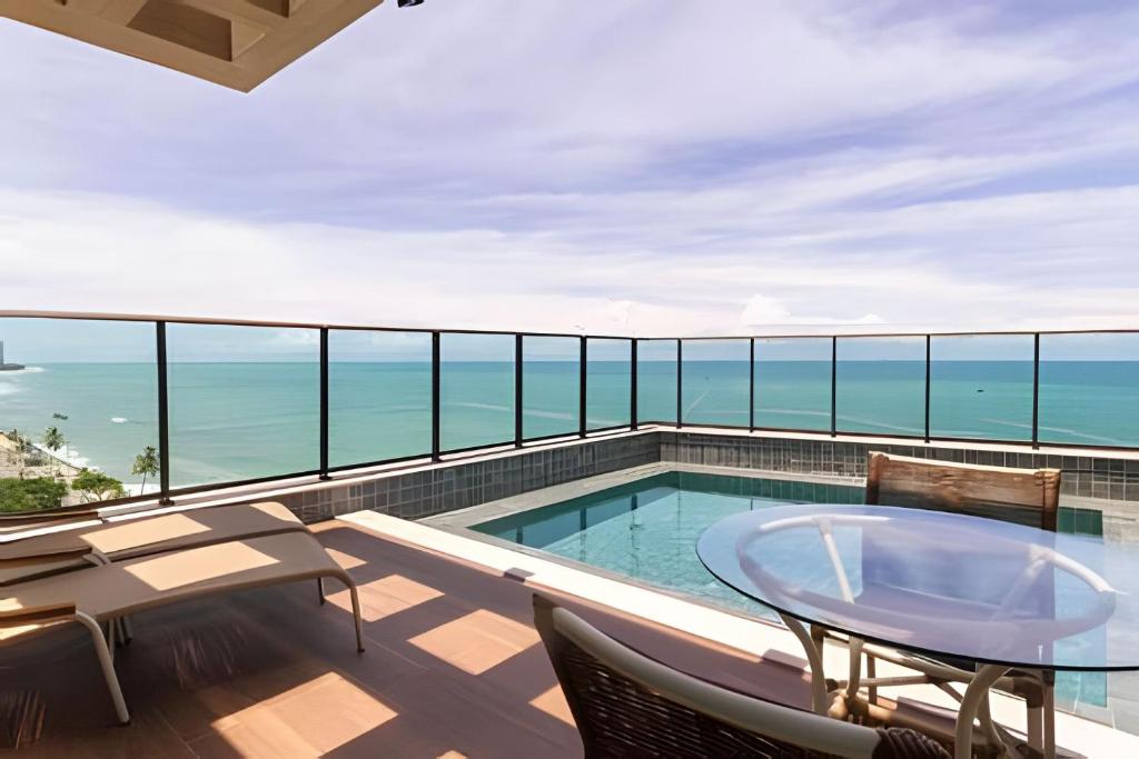 Un balcón con piscina y mesa y sillas. en Beira-Mar Boa Viagem - Ivone Asfora by Bnb Flex, en Recife
